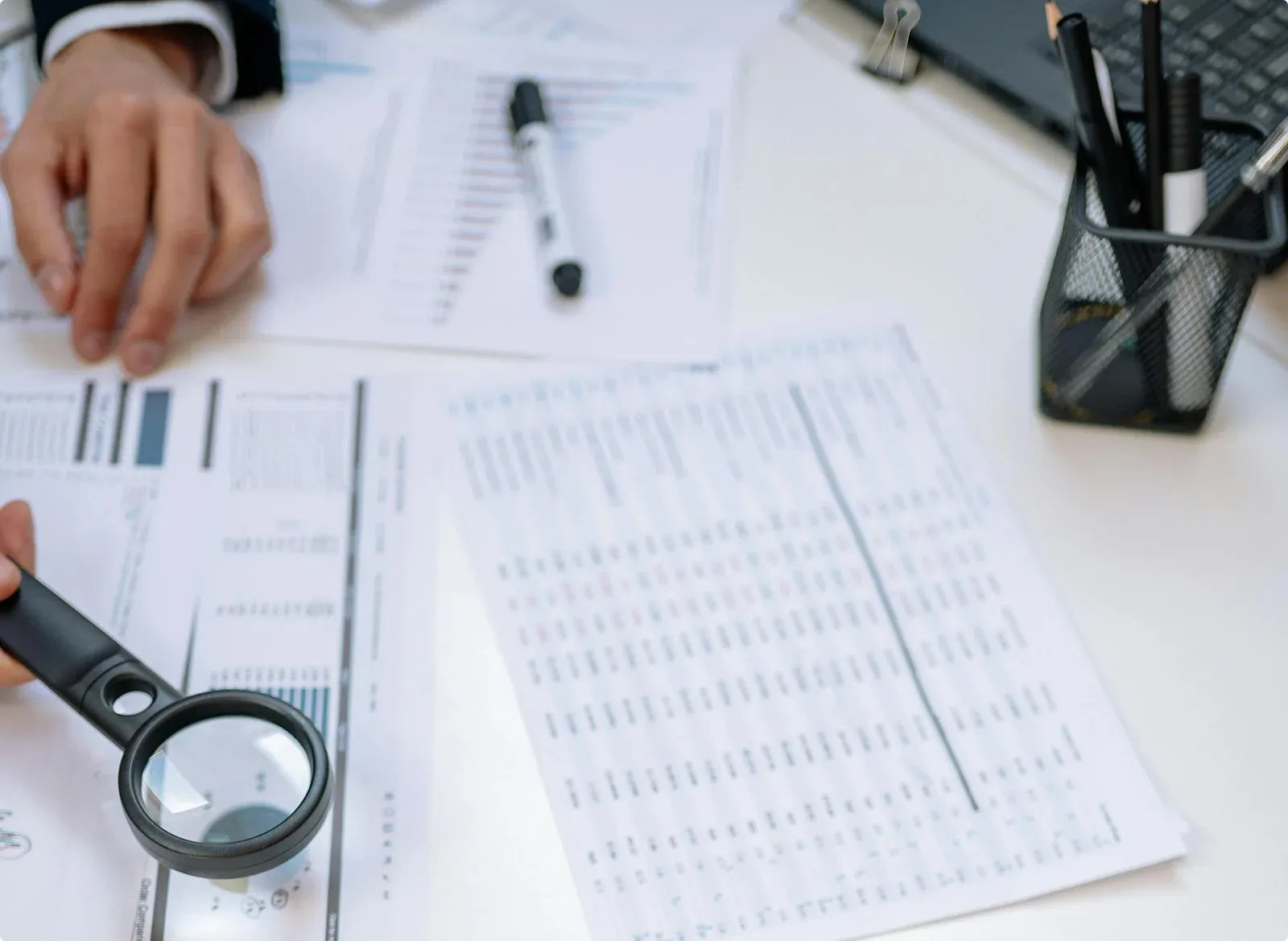 Printed reports being checked with a magnifying glass